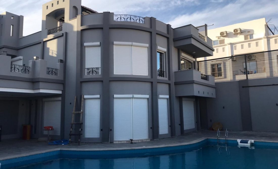 Grey villa with white roller shutters by the pool