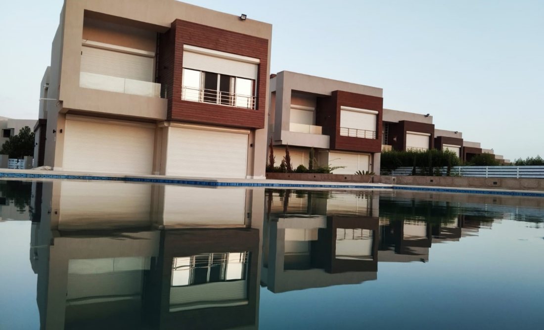 Roller shutters reflected in a villa pool