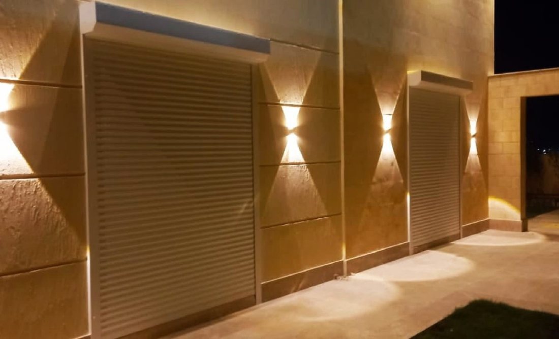 Two roller shutters on a stone-clad wall at night